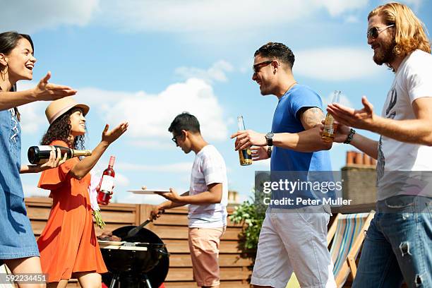 female and male friends greeting at rooftop barbecue - grill friends and beer stock pictures, royalty-free photos & images