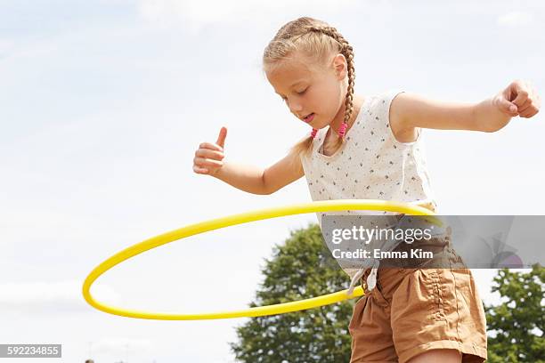 low angle view of girl using hula hoop, arms open looking down - open day 11 stock pictures, royalty-free photos & images