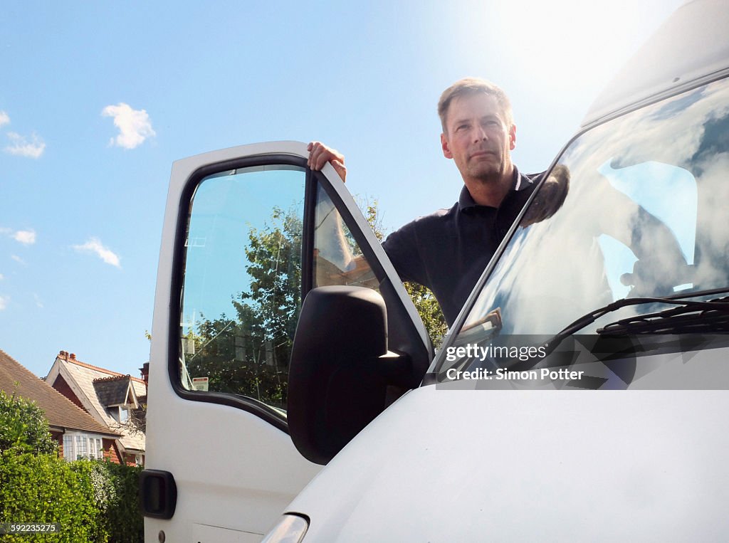 Delivery man looking out from white van on suburban street