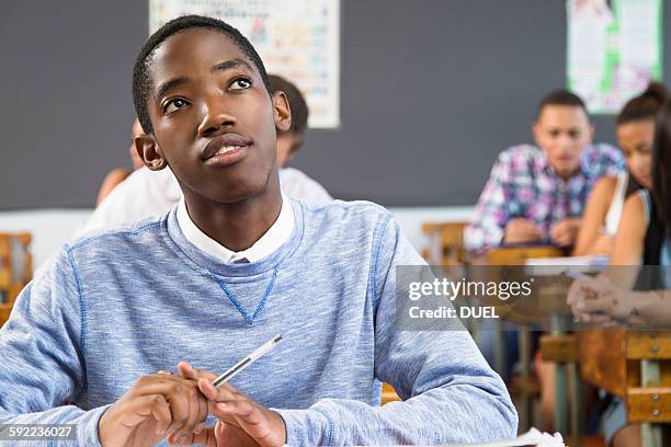 portrait of male student, sitting at desk in classroom - student day dreaming stock pictures, royalty-free photos & images