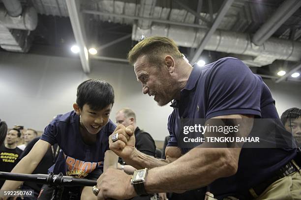 Actor and former California governor, Arnold Schwarzenegger cheers on a young participant on a stationary bicycle during the officiation of the...