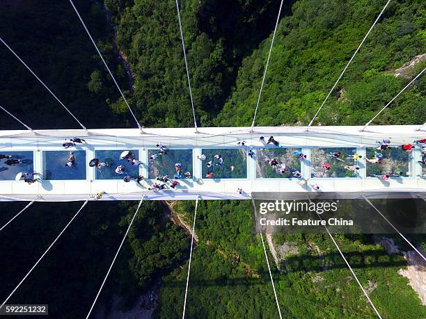 Tourists walk on the glass-floor suspension bridge on the first day of its trial operation on August 20, 2016 in Zhangjiajie, China. The...