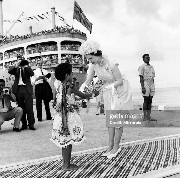 Queen Elizabeth II arrives in Suva, Fiji from the Royal yacht and is presented a bouquet of flowers by Fijian girl Adi Kaunilotuma who sat down in...