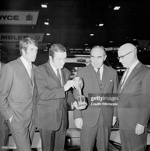 Champion Rally Driver Paddy Hopkirk holds The Jules Rimet Trophy aka Football World Cup Trophy, watched by Geoff Hurst, Sir Alf Ramsey & Lord Stokes...