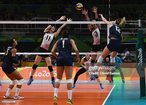 Erika Araki and Saori Kimura of Japan jump for a block while Kelly Murphy of the United States spikes the ball during the Women's Quarterfinal match...