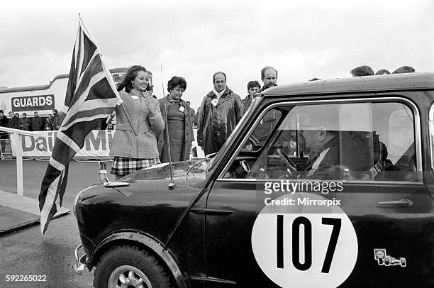 Miss U.K., Sheena Drummond pictured with Union Jack waves off Car No. 107, the blue Austin Cooper S. At the Wheel is co-driver John Miles: in the...
