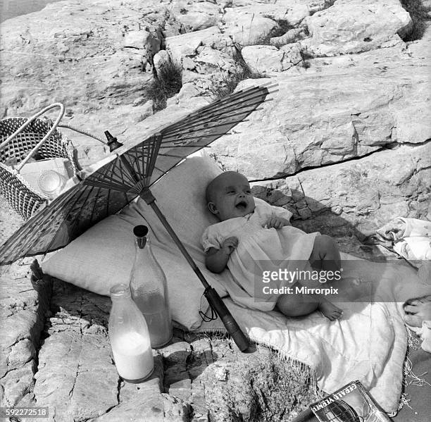 Baby under Sunshade beach pix. The happy baby is 4 months old Beverley Lovelock, whose mummy, of the Parade, Plymouth, took her for a beach picnic....