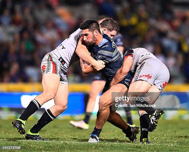 James Tamou of the Cowboys is tackled by Ryan Hoffman and Simon Mannering of the Warriors during the round 24 NRL match between the North Queensland...