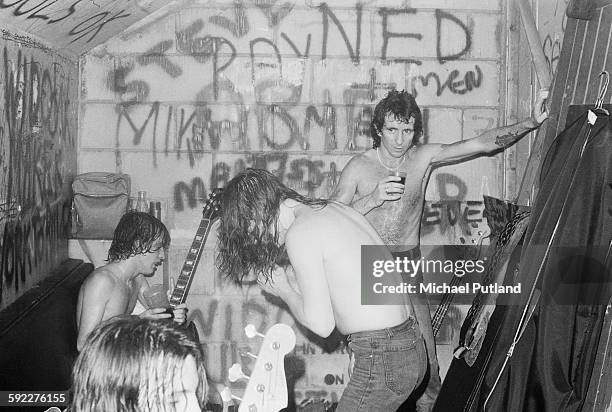 Hard rock group AC/DC backstage after a performance at the Marquee Club on Wardour Street, London, 11th August 1976. Singer Bon Scott is at far...