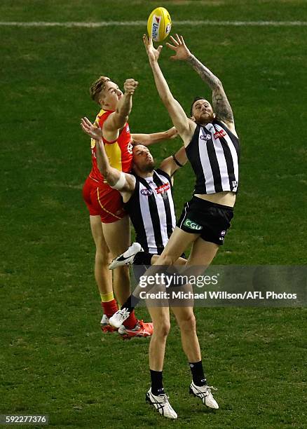 Jeremy Howe of the Magpies marks over teammate Nathan Brown and Tom Lynch of the Suns during the 2016 AFL Round 22 match between the Collingwood...