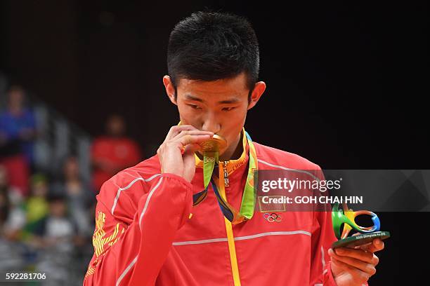 Gold medalist China's Chen Long kisses his medal during the medal presentation ceremony following the men's singles Gold Medal badminton match at the...