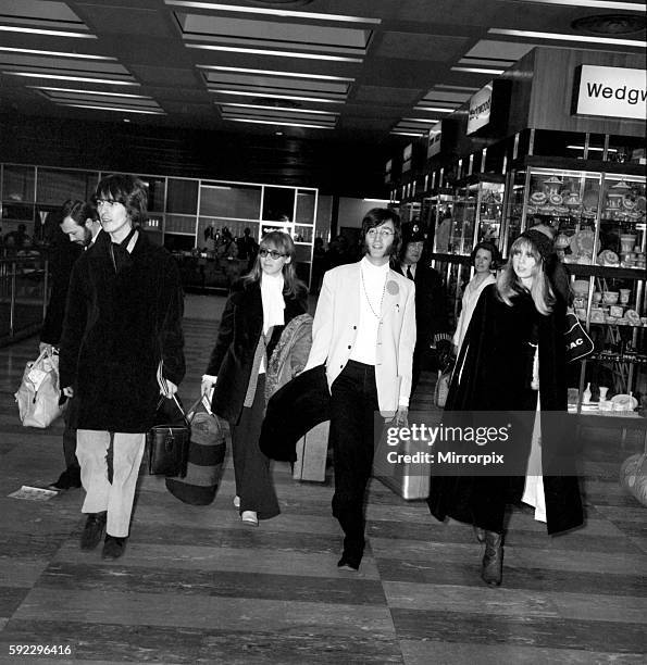 John Lennon and wife Cynthia wearing trouser suit, beret and glasses, with Beatle George Harrison and wife Patti Boyd wearing maxi outfit and her...