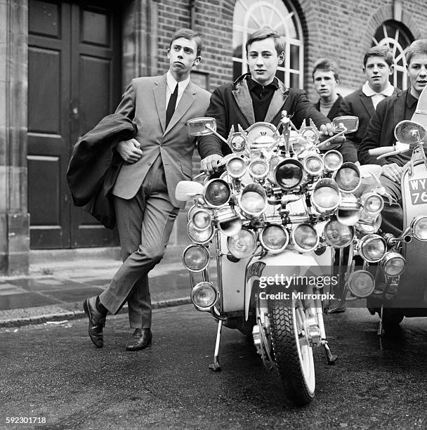 Mods wearing suits and parka's on Motor Scooters covered with extra lights and wing mirrors pose for a group picture in Peckham. 7th May 1964.