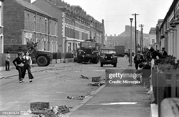 Soldiers, Fireman and local residents survey the damage following rioting on the streets of Belfast. August 1971 71-8167