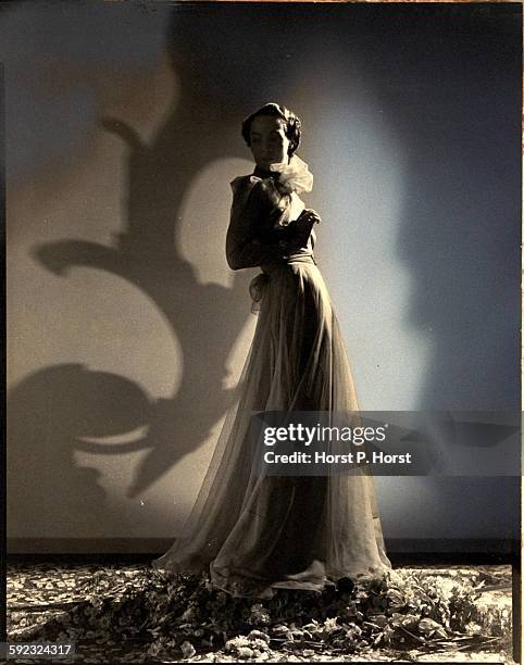 Model wearing a white faille silk dress with umbrella-rib-like pressed seams and a red-and-white ribbon jacket, both by Salon Moderne