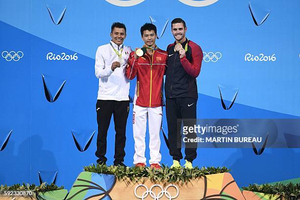 Gold medallist China's Chen Aisen celebrates next to silver medallist Mexico's German Saul Sanchez Sanchez and bronze medallist USA's David Boudia...