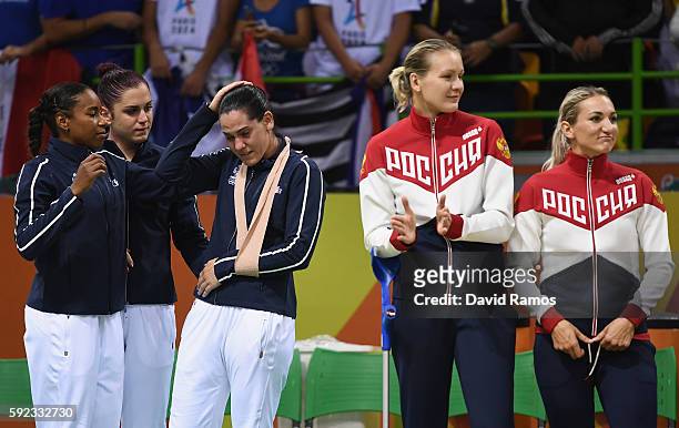Silver medalists Alexandra Lacrabere and her team mates of France react while gold medalists of Russia look on during the medal ceremony for the...