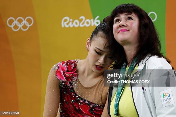 South Korea's Son Yeon Jae reacts next to her coach after competing in the individual all-around final event of the Rhythmic Gymnastics at the...