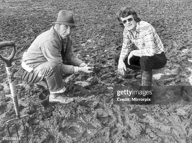 Concerned Eddie McCreadie Chelsea Football Club manager examines the surface water on pitch at Stamford Bridge with groundsman George Anstiss...