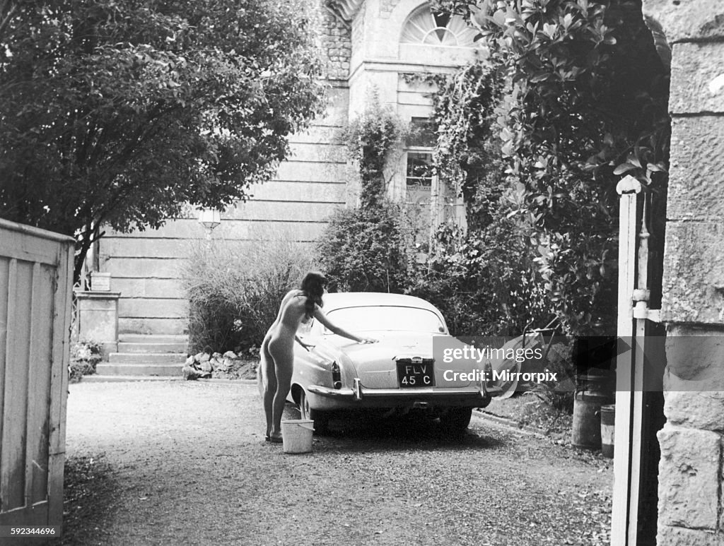 Nude woman cleaning the family car at the Nudist camp near Ventnor on the Isle of Wight.