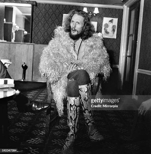 British drummer Ginger Baker, former member of the pop group Cream, in curly shearling sheep wool coat and snakeskin high boots, sitting on a chair,...