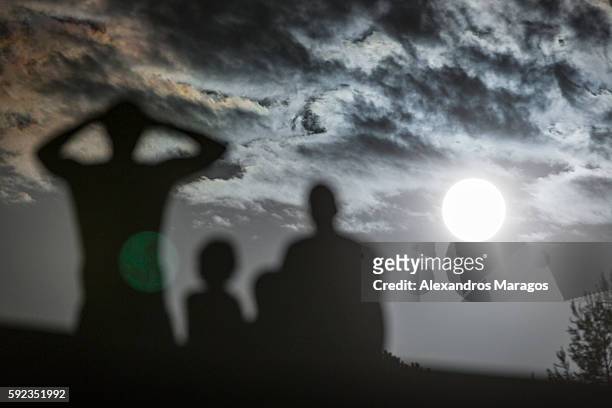 family watching the full moon - alexandros maragos stock pictures, royalty-free photos & images