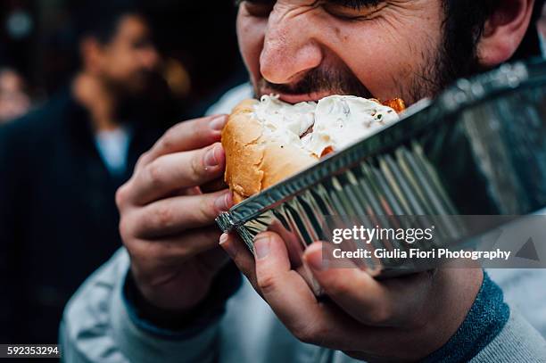 man eating hot dog on the streets - adults eating hamburgers stock-fotos und bilder