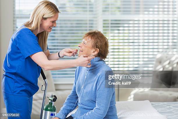 su personal de enfermería de atención médica ayudar a mujer anciana con oxígeno - medical oxygen equipment fotografías e imágenes de stock