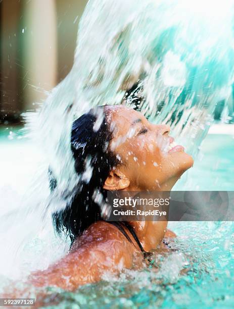 schöne junge frau spritzt unter der kaskade des spa-pools - women swimming pool retro stock-fotos und bilder