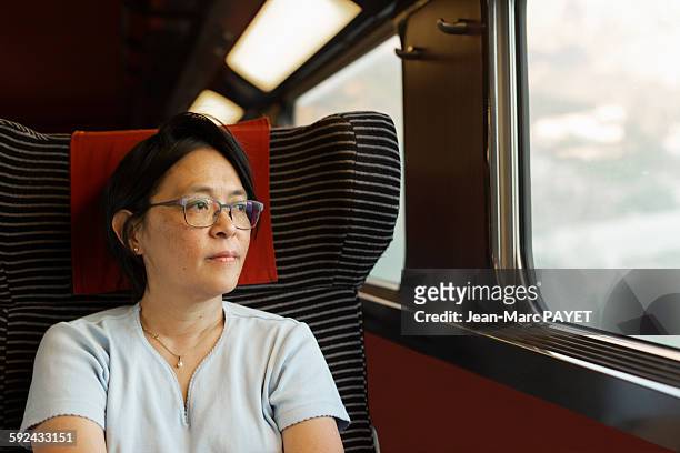 woman looking through window in a train - jean marc payet stock-fotos und bilder