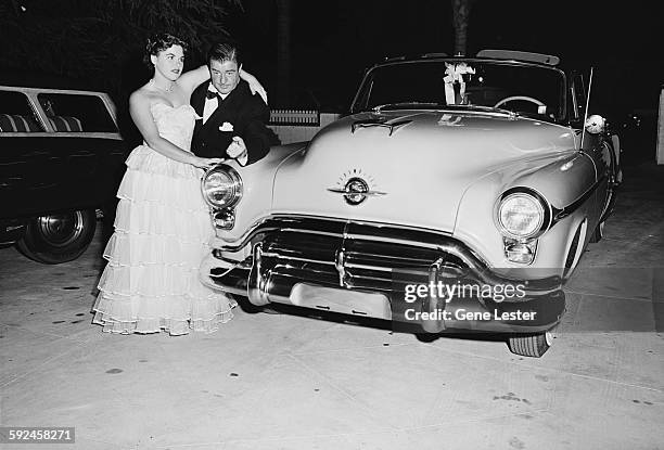 Portrait of American comedian and actor Lou Costello and an unidentified woman as they pose beside an Oldsmobile in the parking lot, September 27,...