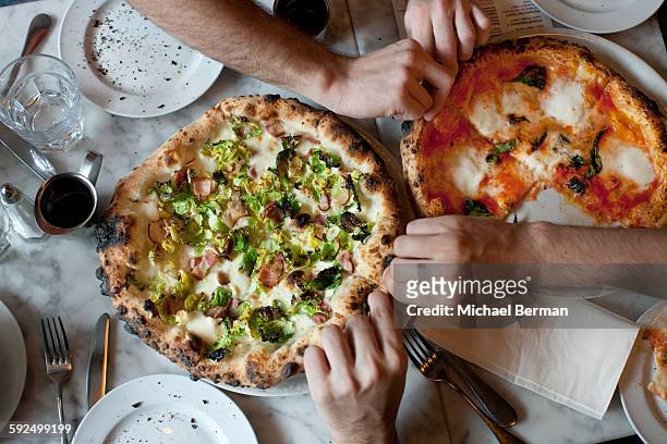 hands reach for naples-style pizza - ピザ ストックフォトと画像
