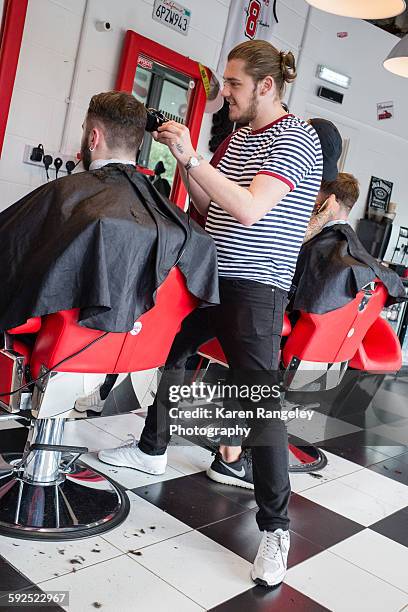 Barber Nathanael chats to client Alex while he styles his hair in cutting edge barbershop in Leeds.