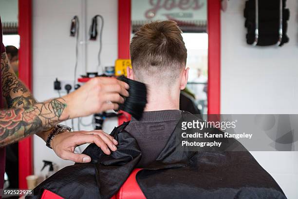 Finishing touches as barber Will brushes away the hair from his clients nape.