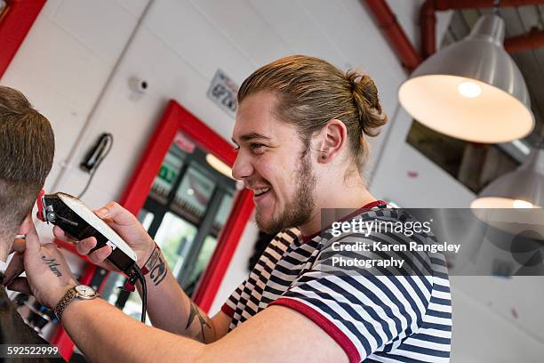 Barber Nathanael enjoys a laugh with his client as he trims his hair