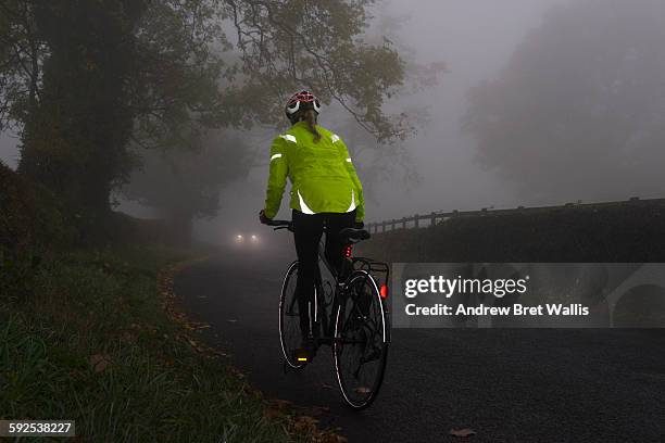 cyclist in high visibility safety wear on the road - fietser stockfoto's en -beelden