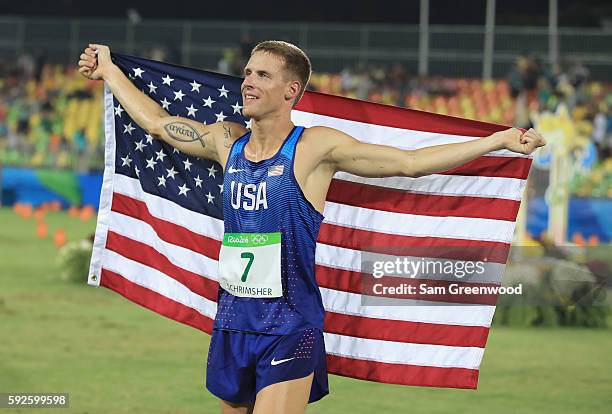 Nathan Schrimsher of USA celebrates with the USA flag after the Modern Pentathlon on Day 15 of the Rio 2016 Olympic Games at Deodoro Stadium on...