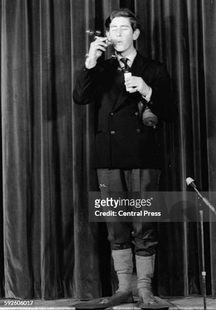 Prince Charles, the Prince of Wales, blowing bubbles on stage as he performs in a student revue called 'Quiet Flows The Don', at Trinity College,...
