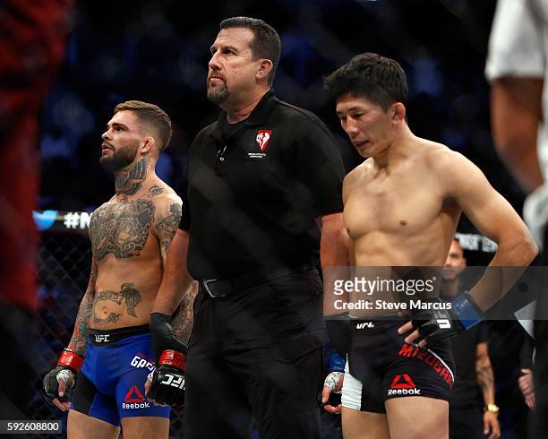 Referee John McCarthy stands with Cody Garbrandt and Takeya Mizugaki after their bantamweight bout at the UFC 202 event at T-Mobile Arena on August...