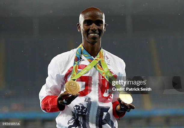 Gold medalist Mohamed Farah of Great Britain holds both his 5000 meter and 10000 meter gold medals on the podium during the medal ceremony for the...