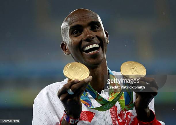 Gold medalist Mohamed Farah of Great Britain holds both his 5000 meter and 10000 meter gold medals on the podium during the medal ceremony for the...