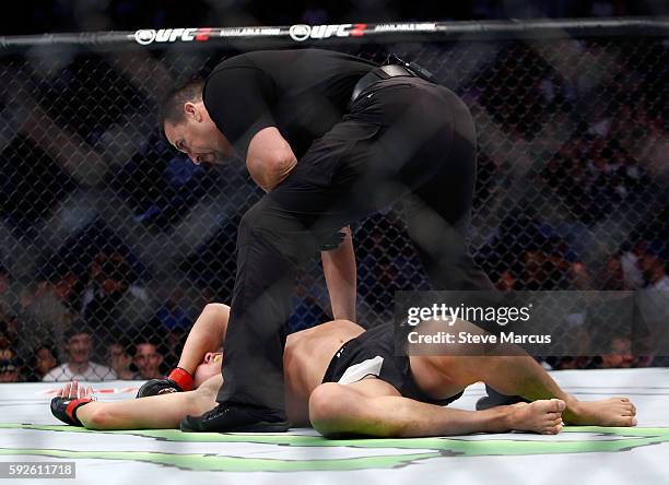 Referee John McCarthy checks on Hyun Gyu Lim after his first-round TKO loss to Mike Perry in their welterweight bout at the UFC 202 event at T-Mobile...