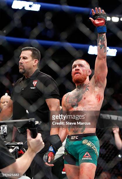 Referee John McCarthy stands next to Conor McGregor as he celebrates his majority-decision victory over Nate Diaz in their welterweight rematch at...