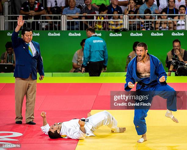 Referee Akinobu Osako of Japan signals ippon while Travis Stevens of the United States celebrates having strangled strangled Avtandili Tchrikishvili...