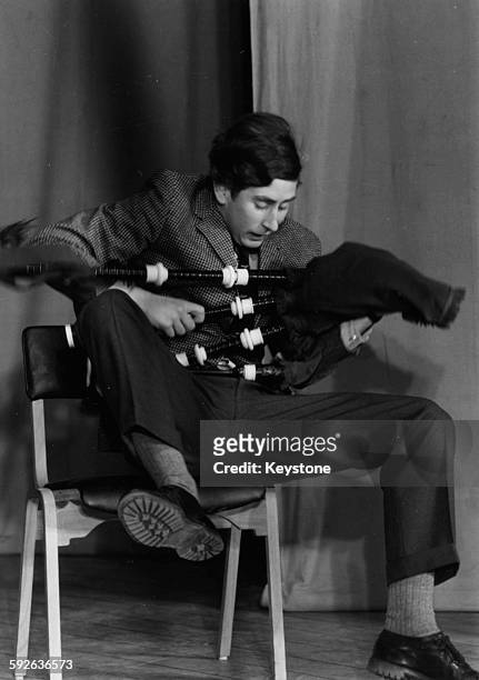 Prince Charles, the Prince of Wales, joking around with a set of bagpipes as he appears on stage in a student revue in 'Quiet Flows the Don', at...
