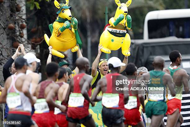 Australia's supporter cheer while athletes run during the Men's Marathon athletics event at the Rio 2016 Olympic Games in Rio de Janeiro on August...