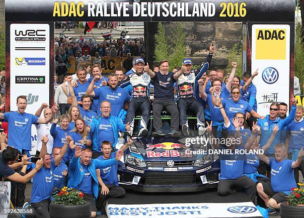 French driver Sebastien Ogier and his co-pilot Julien Ingrassia sit next to Volkswagen motorsport manager Jost Capito as they celebrate their victory...