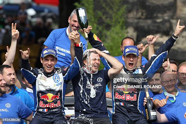 French driver Sebastien Ogier and his co-pilot Julien Ingrassia sit next to Volkswagen motorsport manager Jost Capito as they celebrate their victory...