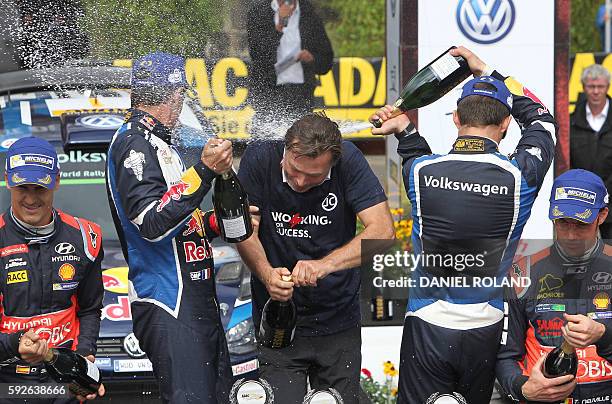 French driver Sebastien Ogier and his co-pilot Julien Ingrassia spray champagne onto Volkswagen motorsport manager Jost Capito as they celebrate...