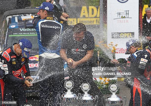 French driver Sebastien Ogier and his co-pilot Julien Ingrassia spray champagne onto Volkswagen motorsport manager Jost Capito as they celebrate...